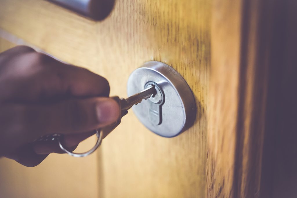 Man opening the door to his home with his steel key