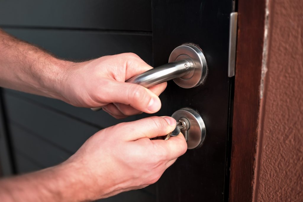 Man hand opening black door with key